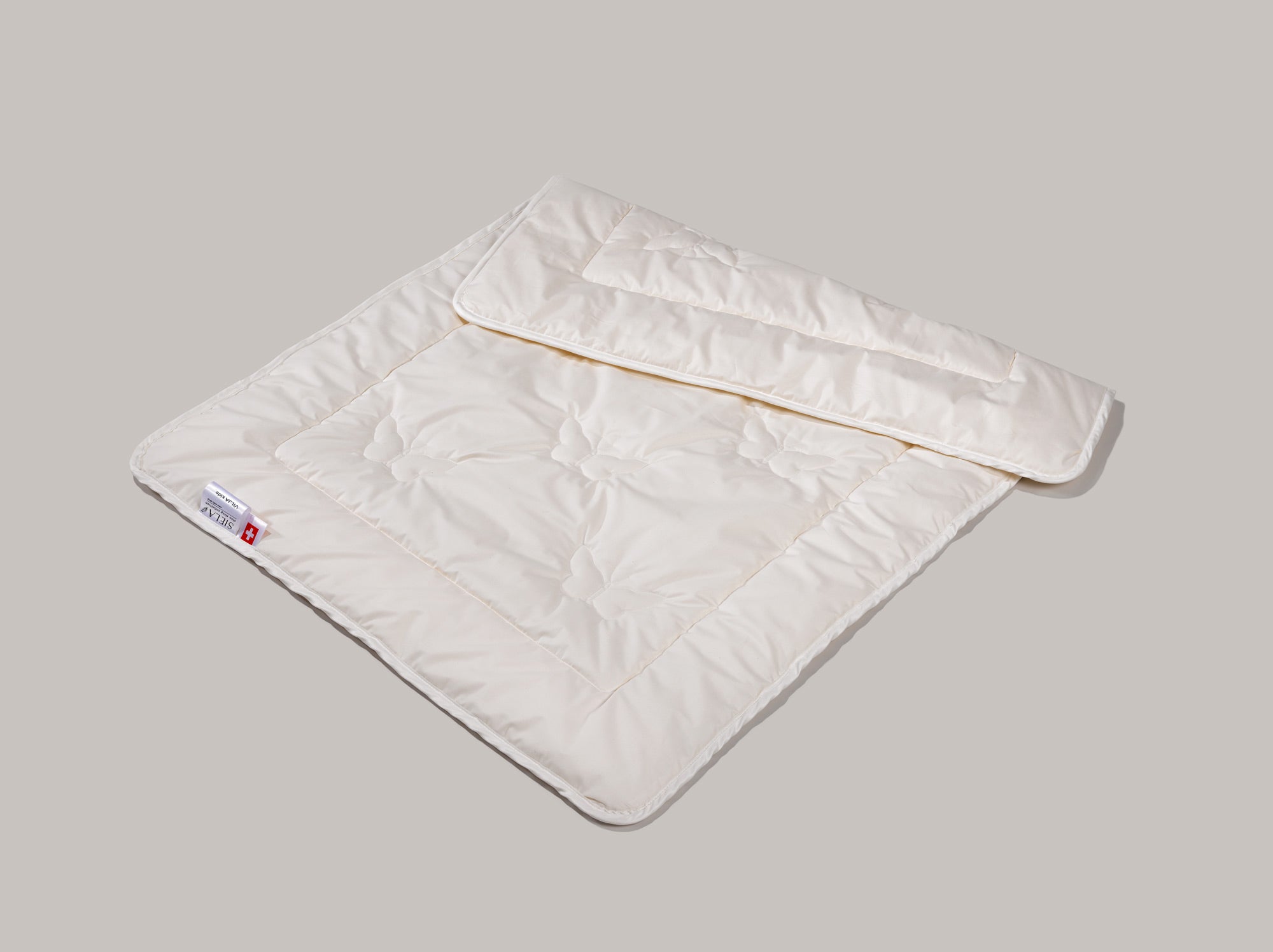 Dad Kinder Maisfaserduvet mit der Schmetterlingsteppunk liegt halbiert auf grauem Grund.