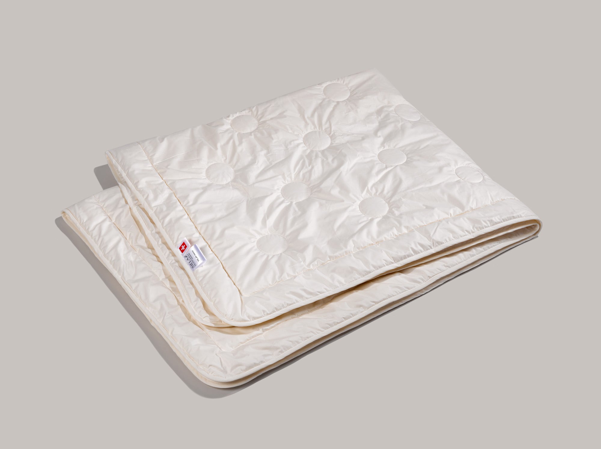 Das Maisfaserduvet ligt zusammengelegt auf grauem Grund.