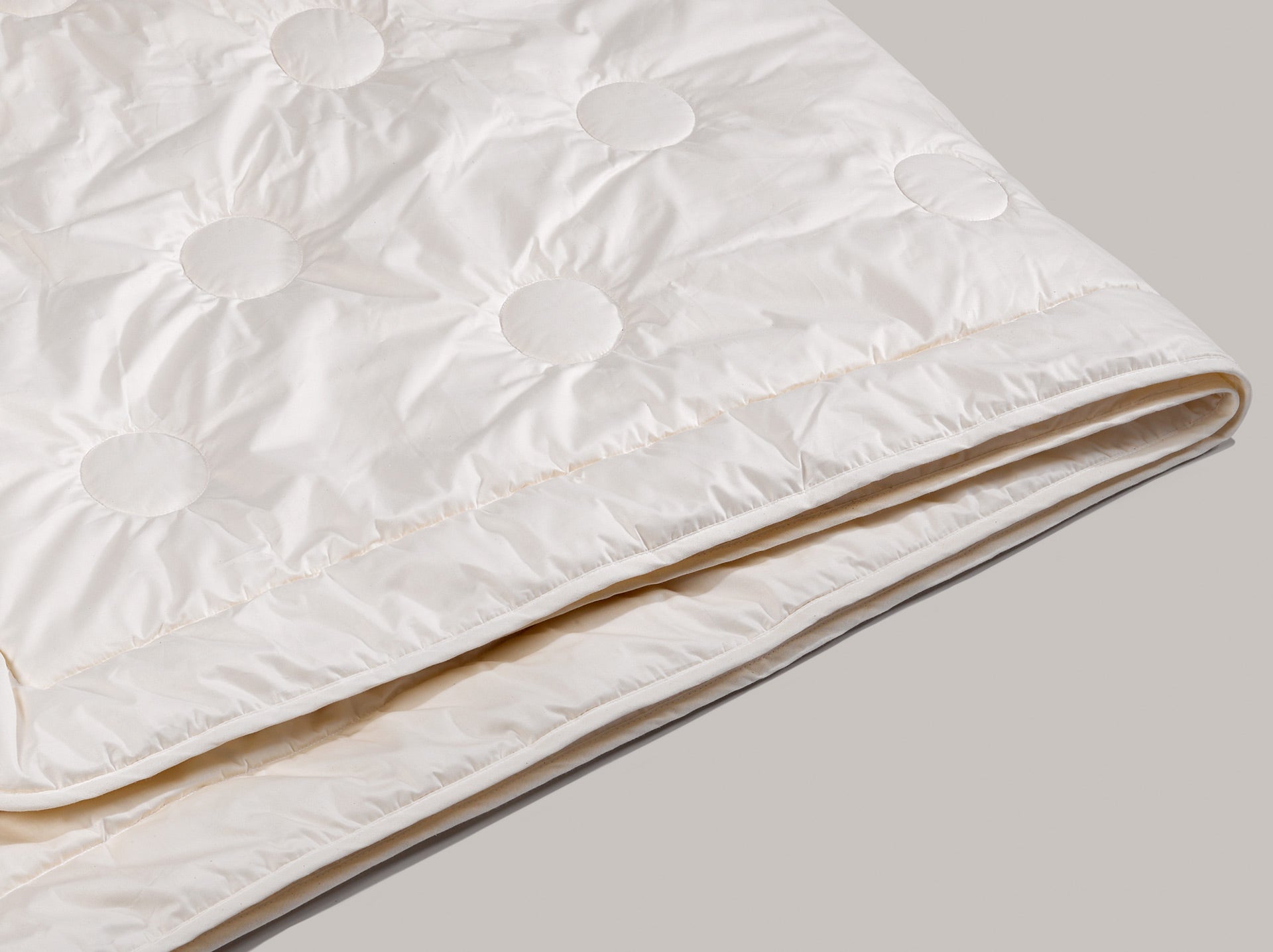 Das Maisfaserduvet mit dem runden Steppmuster im Detail. Die Kanten des Duvets sind mit einem Band versäubert.